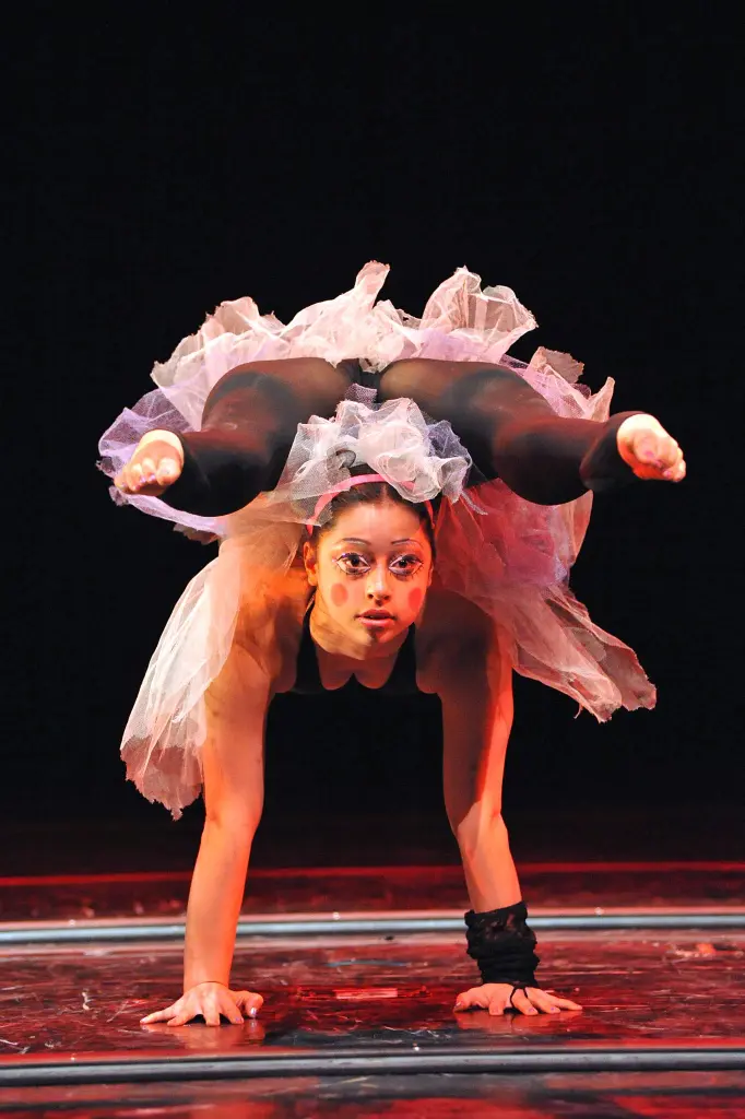 Leilani Lemuela Franco, une contorsionniste en tutu, se tient en équilibre sur ses mains, les jambes repliées sur ses épaules, faisant preuve d'une souplesse et d'une force incroyables.