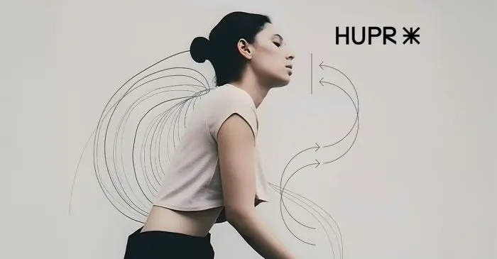 Une femme aux cheveux noirs coiffés en chignon se penche en avant dans une chemise de couleur claire. Des flèches et des lignes noires incurvées suggèrent le mouvement ou la circulation de l'air. Le texte HUPR* apparaît à droite, marquant le lancement officiel : le site web de HUPR est en ligne !.