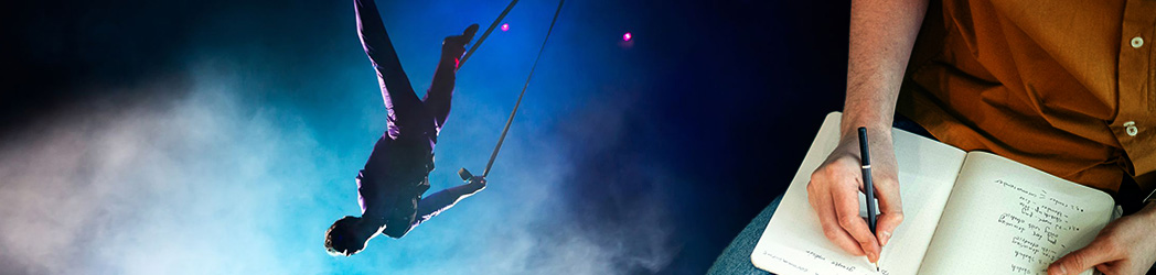 Une personne fait des acrobaties en l'air sur un trapèze sous un éclairage dramatique, tandis qu'une autre personne prend des notes dans un carnet avec un stylo, assise et vêtue d'une chemise brune.
