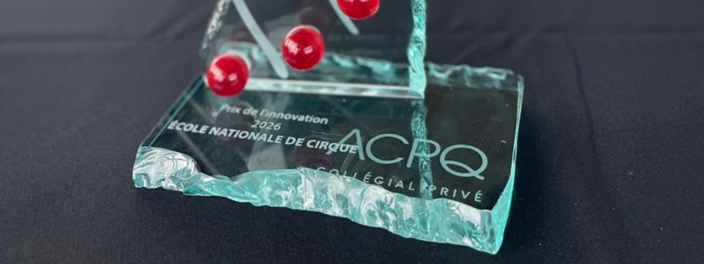 Un trophée en verre orné de sphères rouges porte l'inscription gravée suivante : « Prix de l'Innovation 2026 École Nationale de Cirque ACRPQ Collégial Privé », sur fond sombre.